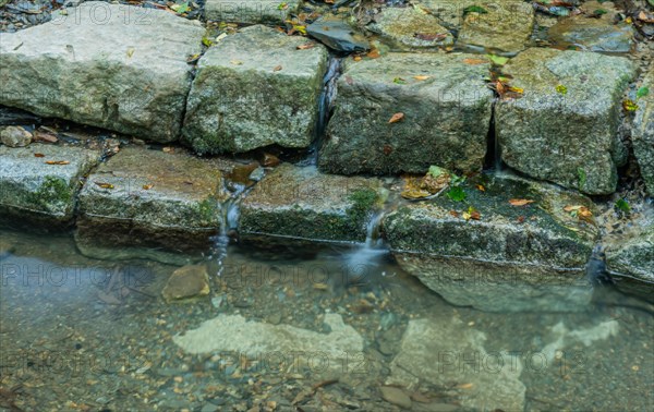 Closeup of shallow man made stream cascading over flat stones on sunny summer day in South Korea