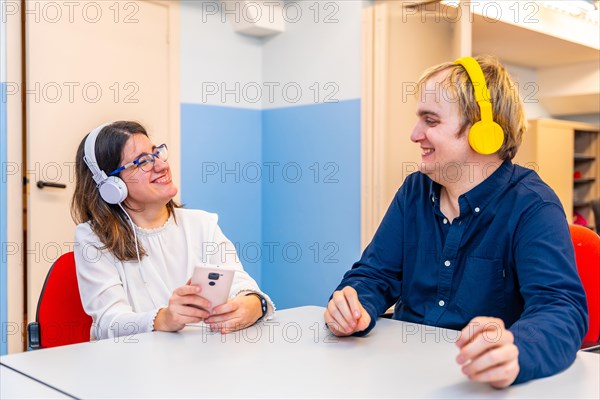 Mental disabled friends sharing music using phone and headphones in a day care center
