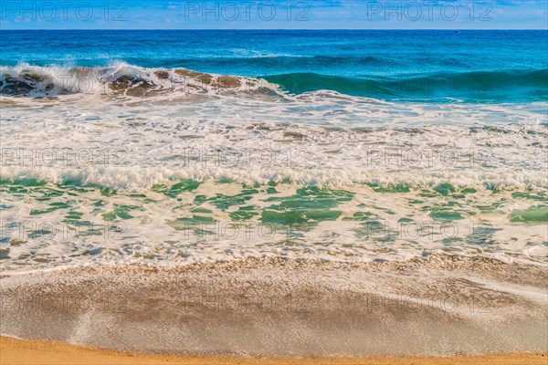 Seascape of whitecaps and waves as tide rolls in to shore on beautiful winter morning under partly cloudy sky, in South Korea