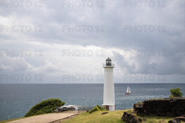 White lighthouse on a steep coast. Dramatic clouds with a view of the sea, pure Caribbean at Le Phare du Vieux-Fort, on Guadeloupe, French Antilles, France, Europe