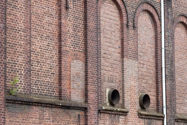 Weathered brick wall of a historic building with arched windows
