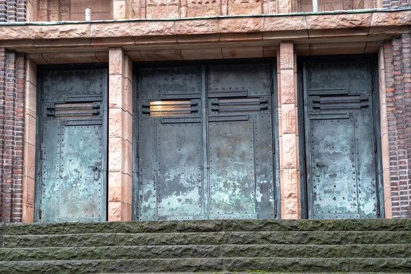Three old, weathered metal doors on a brick facade