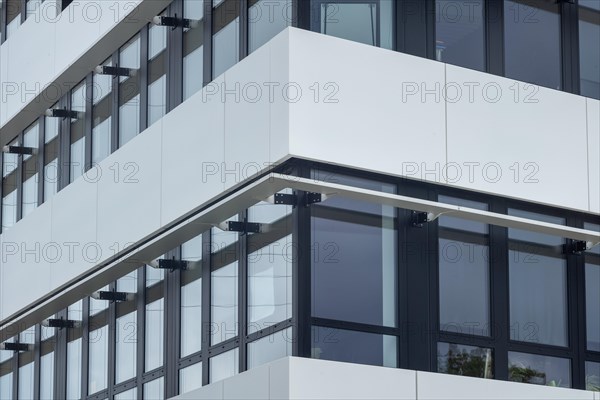 View of a modern office building with glass windows and white panels, symmetrical architecture