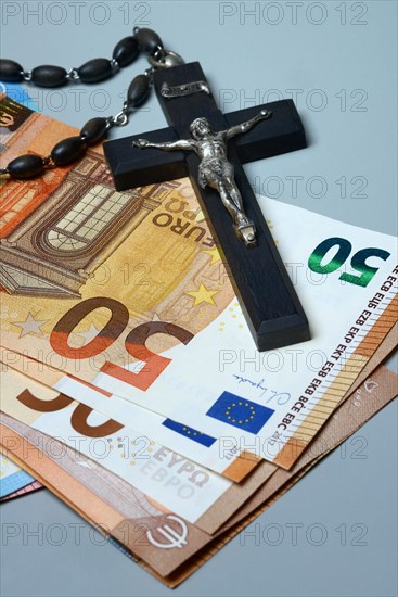 Crucifix and banknotes, church and money, church tax