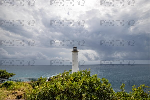 White lighthouse on a steep coast. Dramatic clouds with a view of the sea, pure Caribbean at Le Phare du Vieux-Fort, on Guadeloupe, French Antilles, France, Europe