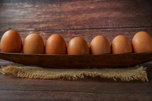 Fresh eggs in a wooden bowl on a burlap cloth on a wooden table