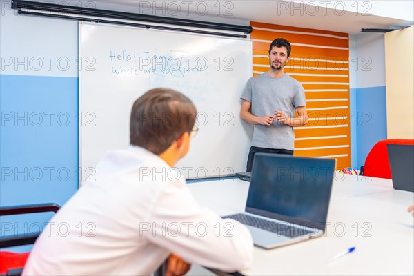 Man with down syndrome using laptop during IT teacher explanation at class