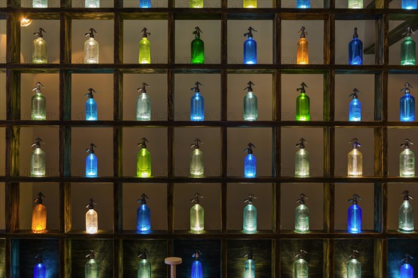 Colourful bottles on shelf, soda bottles, colourful, illuminated, order, colourful, glass, primary colours, bar, restaurant, gastronomy, orderly, decoration, decorated, soda dispenser, art, presentation, pattern, compartments, structure, drink, drinks, texture, background, light, lighting, local