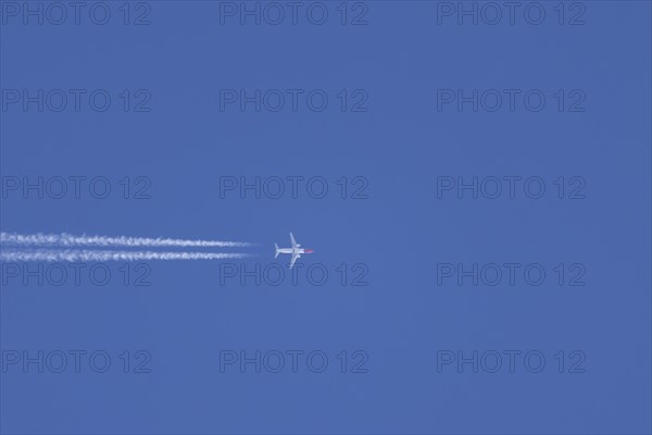 Boeing 737 jet aircraft in flight with a contrail or vapour trail behind in the sky, England, United Kingdom, Europe
