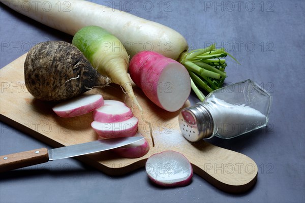 Various radishes on a wooden board, cut up and sliced