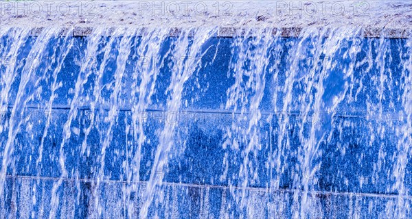 Blue-hued man-made waterfall streaming down a wall, in South Korea