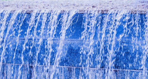 Blue-hued man-made waterfall streaming down a wall, in South Korea