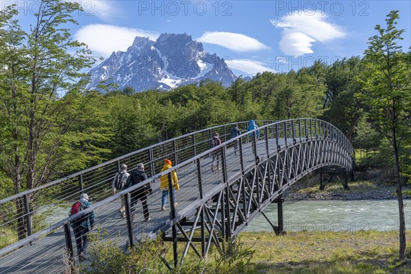 Tourists walk across a bridge over a tributary of Lago Grey, Torres del Paine National Park, Parque Nacional Torres del Paine, Cordillera del Paine, Towers of the Blue Sky, Region de Magallanes y de la Antartica Chilena, Ultima Esperanza Province, UNESCO Biosphere Reserve, Patagonia, End of the World, Chile, South America