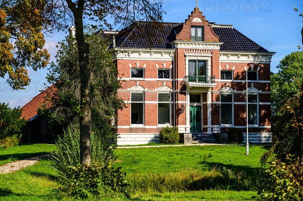A traditional country house surrounded by trees under a blue sky with clouds, Winschoten, Groningen, Netherlands