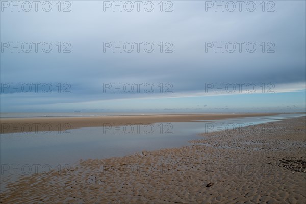 A vast beach with puddles of water under a cloudy sky, radiating a calm atmospherel, DeHaan, Flanders, Belgium, Europe