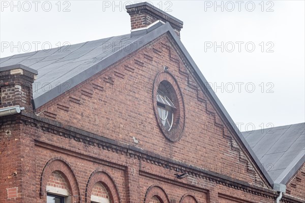 Top of a historic building with a round window and brick facade