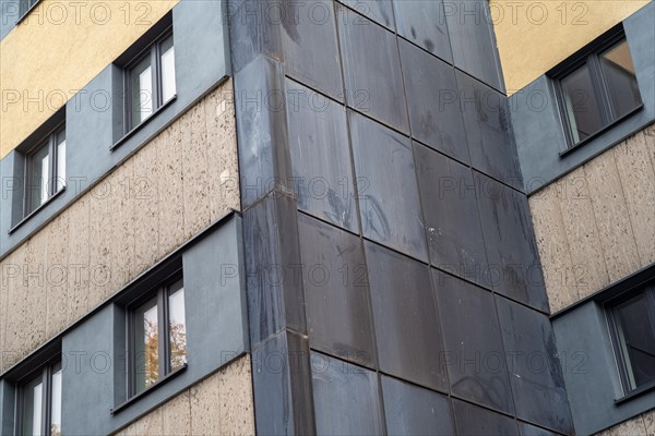 Dark panels on the corner of the building contrast with the light-coloured concrete facade and windows