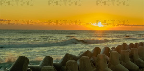 Beautiful sunset scene over the ocean with waves crashing against a breakwater, in South Korea