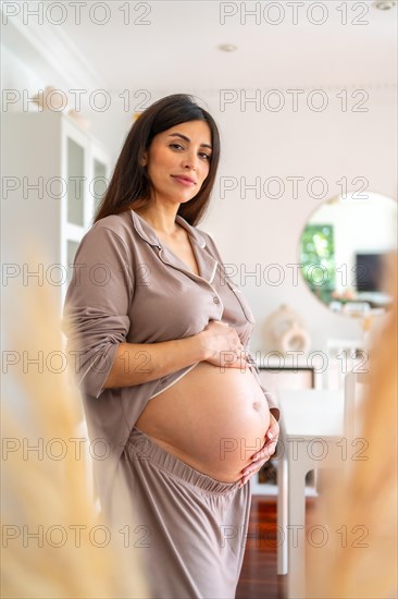 Vertical portrait of a beauty pregnant woman standing in the future baby room