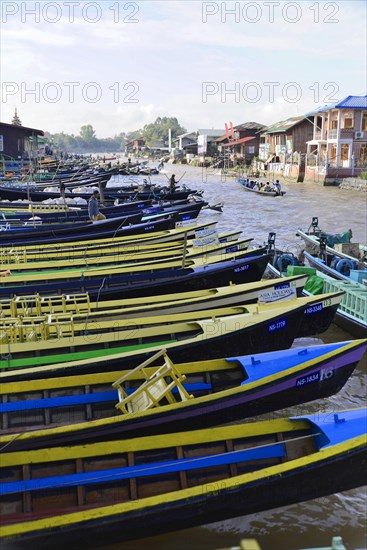 Row of colourful boats on a river bank with houses in the background, Pindaya, Inle Lake, Myanmar, Asia