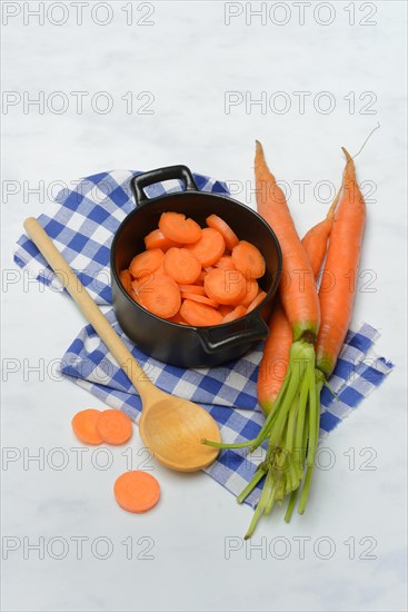 Carrot slices in pots and wooden spoon, carrot (Daucus carota)