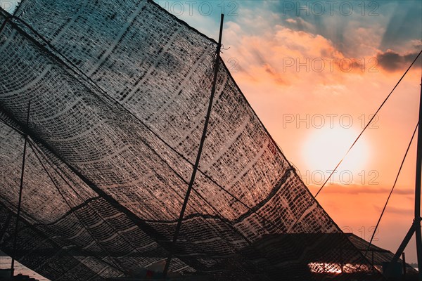 Close up of fishing nets hanged to dry and backlit by the sunset light in Mekong Delta, Vietnam, Asia