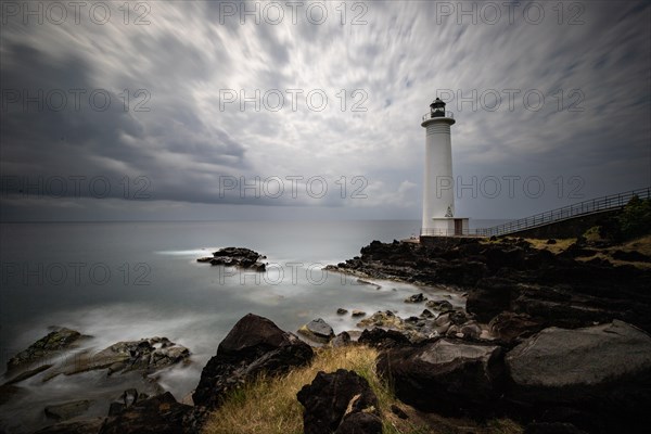 White lighthouse on a steep coast. Dramatic clouds with a view of the sea, pure Caribbean at Le Phare du Vieux-Fort, on Guadeloupe, French Antilles, France, Europe