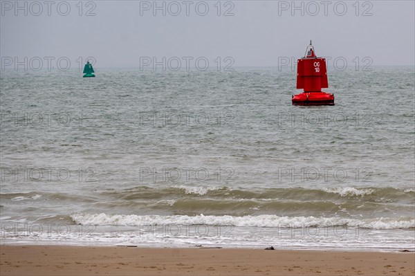 Red and green buoys mark the waterway on the calm sea