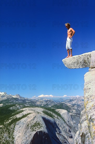 A man makes a test of courage and stands on a ledge at the top of Half Dome, 600 metres above the ground, Yosemite Valley, California, USA, retro, vintage, old, retro, vintage, old, North America