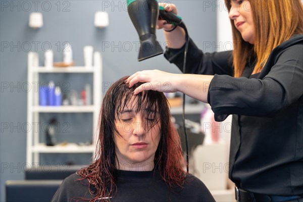 Hairdresser drying the hair of a patient woman in the salon