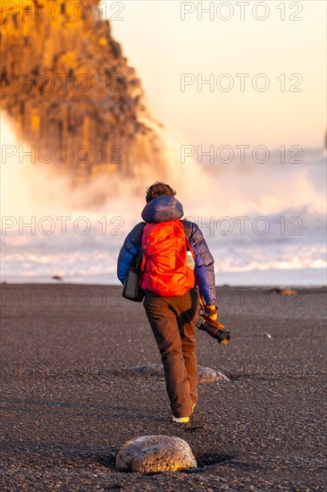 Adventurous photographer woman in winter in Iceland visiting the Reynisfjara Black Sand Beach