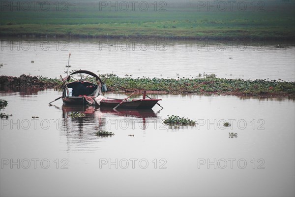 Early morning scene of a fishing boat in a calm river with reflections, Ninh Binh, Vietnam, Asia