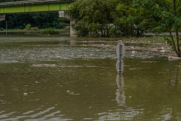 Round traffic signs and trees near bridge submerged in flooded river after torrential monsoon rains in Daejeon South Korea
