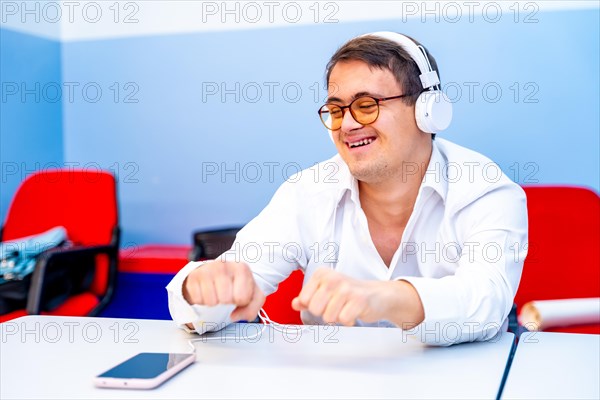 Man with down syndrome dancing sitting while listening to music using headphones and mobile