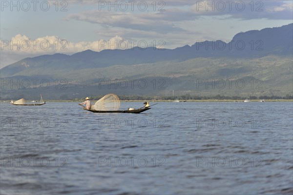 Tranquil scene with a fisherman on his boat, green mountains in the background, Inle Lake, Myanmar, Asia