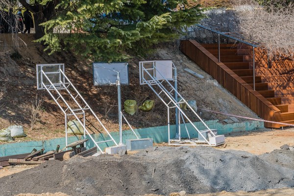 Construction equipment and a pile of earth sit near wooden stairs under a bright sun, in South Korea