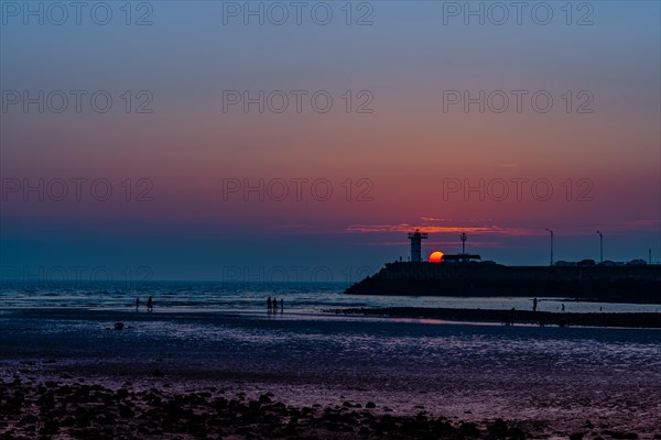 Silhouette of a lighthouse against a gradient sunset sky along the coastline, in South Korea