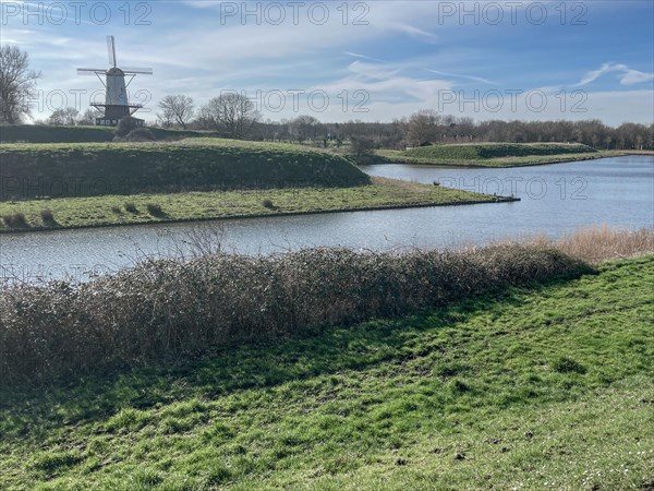 A traditional windmill stands picturesquely on the banks of a river