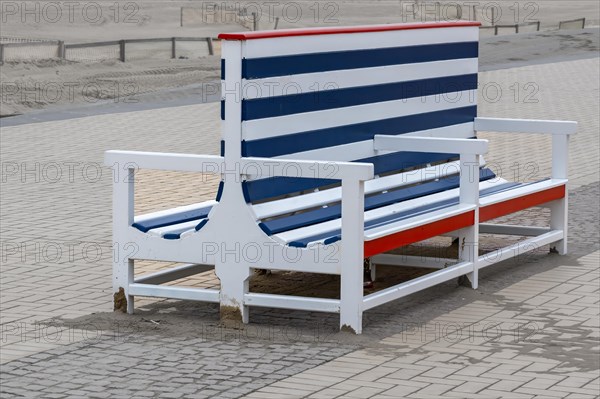 A large, empty beach chair with red, blue and white stripes stands on a cobbled path, Zeebrugge, Flanders, Belgium, Europe