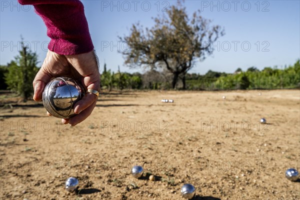 Playing boule in Portugal. Man's hand in the foreground