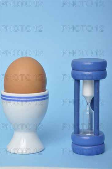 Boiled egg and hourglass on a blue background