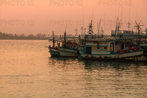 Moored fishing boats bask in the warm glow of the sunset in Koh Sdach Island in Cambodia