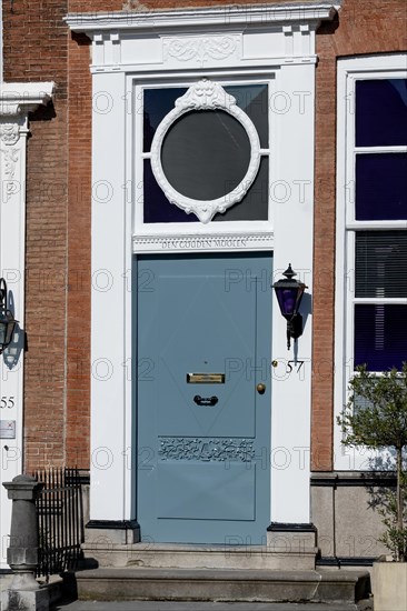 Elegant blue door with oval window on a historic building with lantern next to it, Middelburg, Zeeland, Netherlands