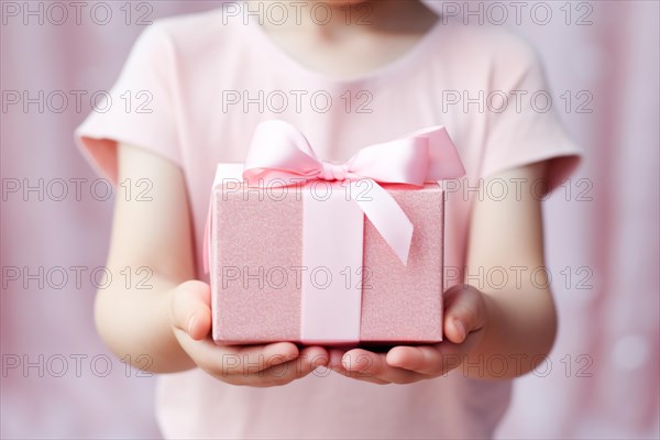 Child holding pink mother's day ift with silk ribbon. KI generiert, generiert AI generated