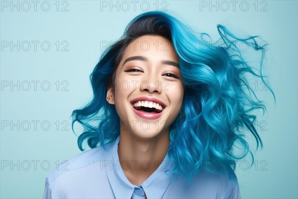 Happy laughing Asian woman with unusual blue hair in front of studio background. KI generiert, generiert AI generated