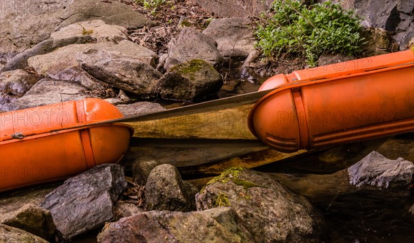 Closeup of two large orange floats discarded in a woodland stream surrounded by rocks and boulders in South Korea