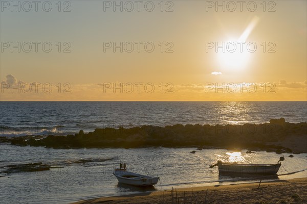 A peaceful sunset by the sea with boats and rocks in the golden light of the evening sun, Finikounda, Pylos-Nestor, Messinia, Peloponnese, Greece, Europe