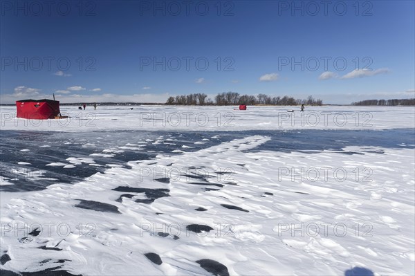 Winter, red fishing hut with snow drifts on a frozen riverscape, Saint Lawrence River, Province of Quebec, Canada, North America