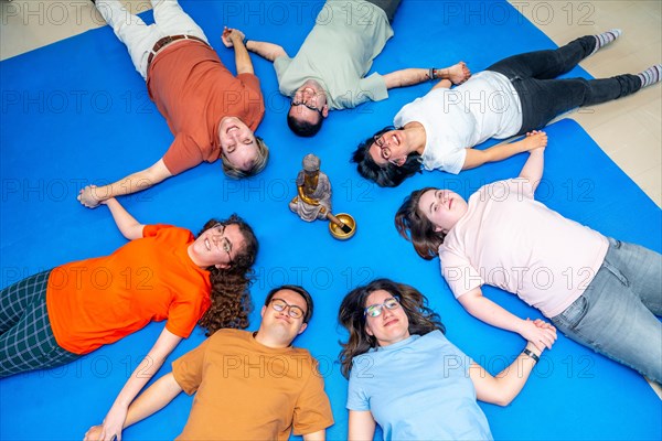 Disabled people lying on the floor meditating together holding hands and closing eyes