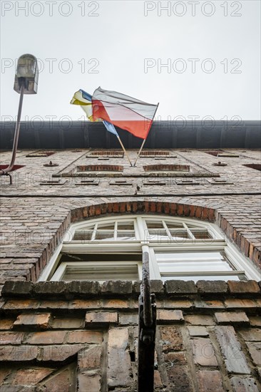 Polish and Ukrainian flag waving together on brick house in Katowice Nikiszowiec, southern Poland